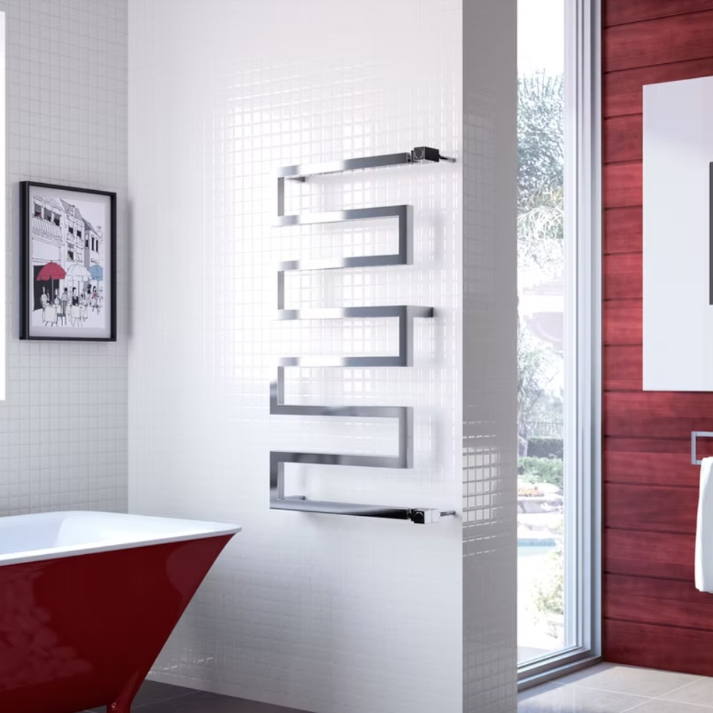 Lifestyle image of the Radox Serpentine 1010mm x 500mm Chrome Designer Towel Rail mounted on a white bathroom wall, next to a red bathtub